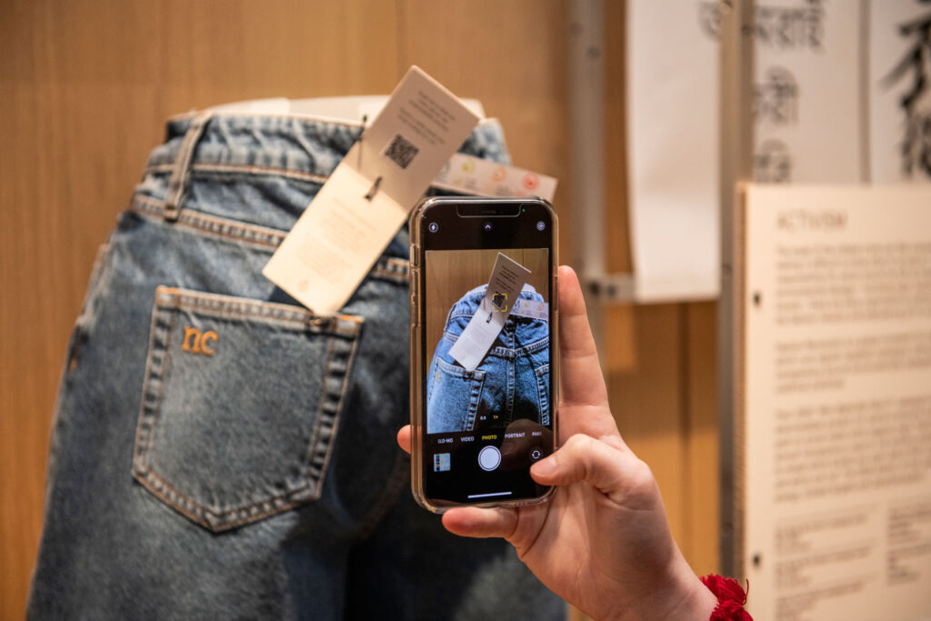 A visitor using their mobile phone to learn more about a pair of jeans