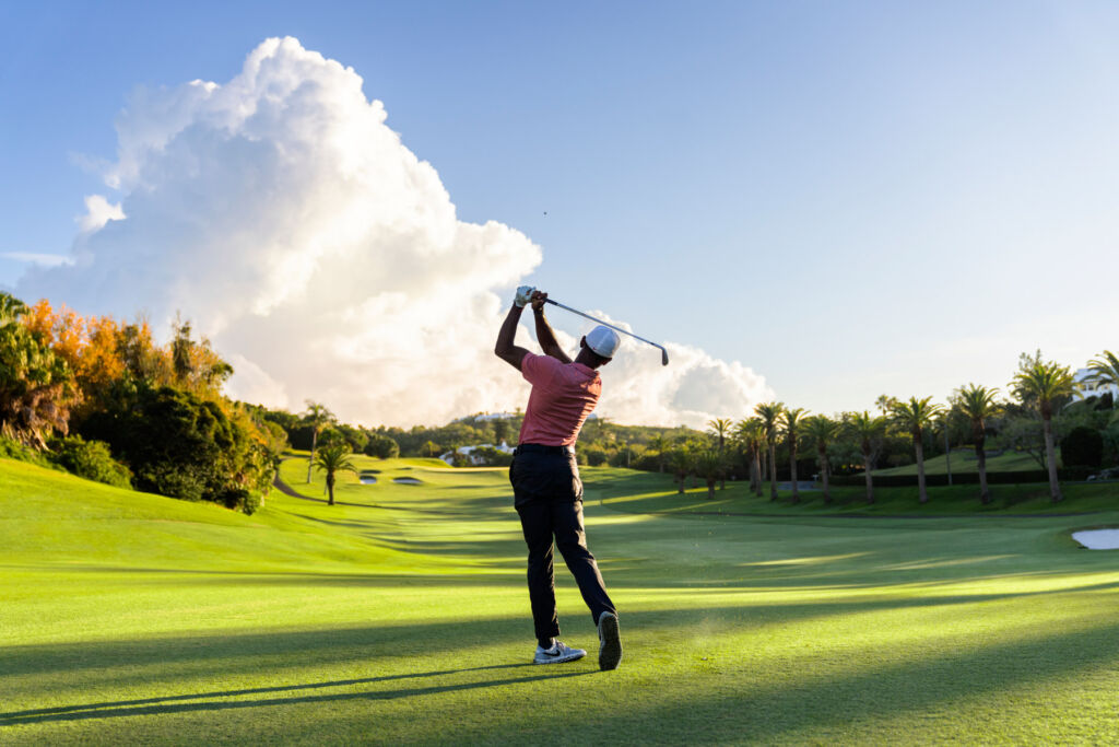 A golfer hitting a ball down a fairway