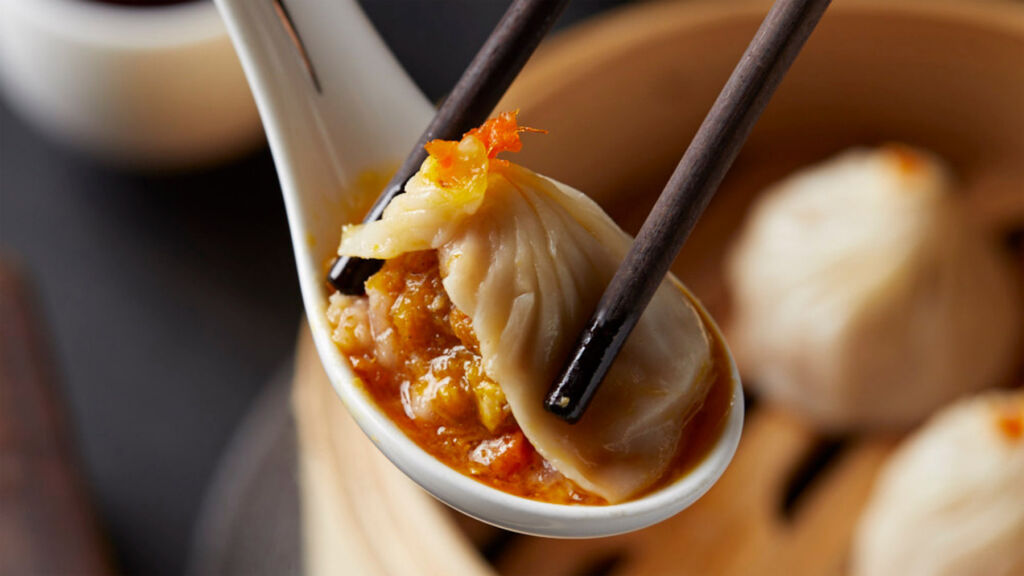 Chopsticks taking a dumpling off a spoon