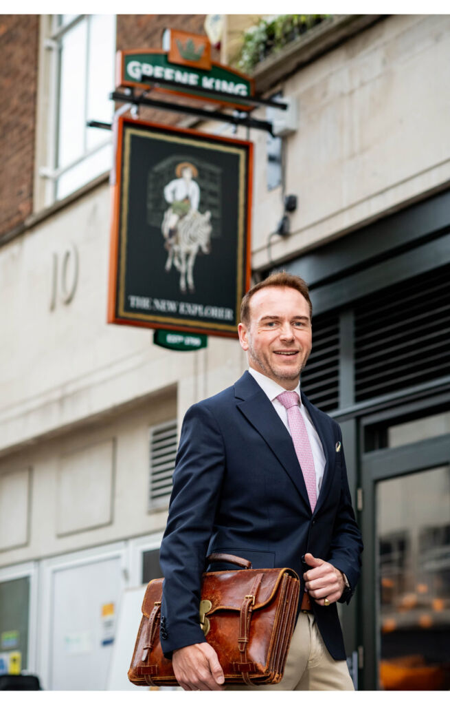 Mr Harrold walking past the entrance to a Greene King pub