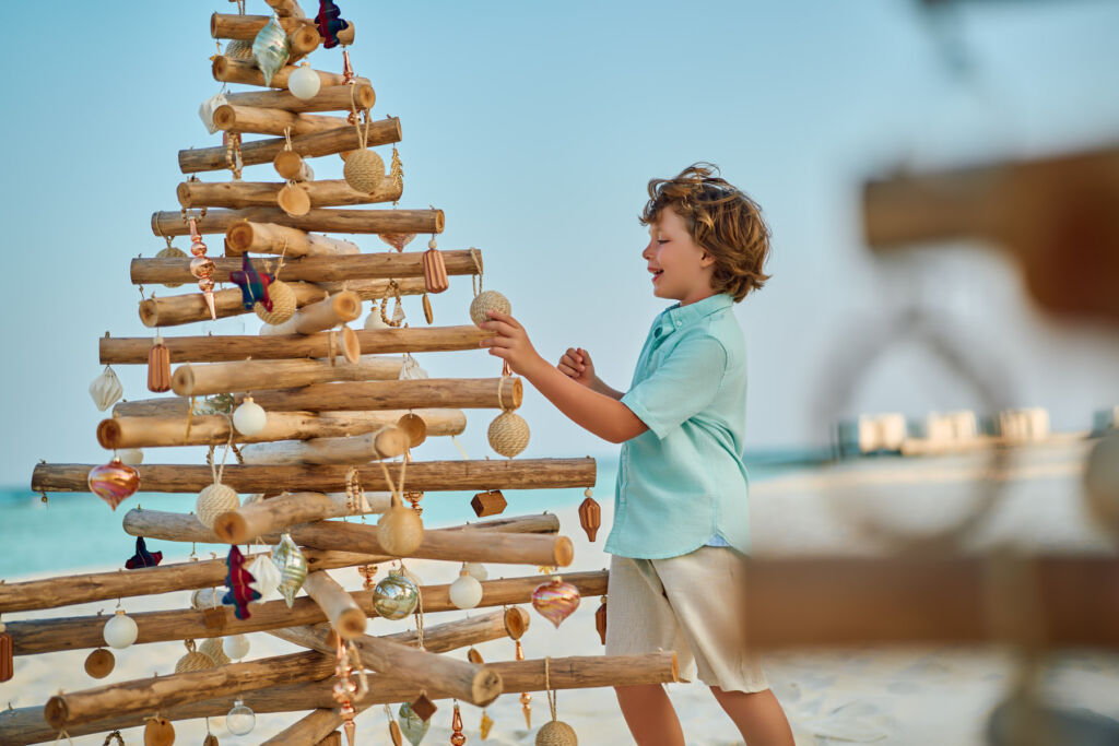 A young boy playing with a wooden tree