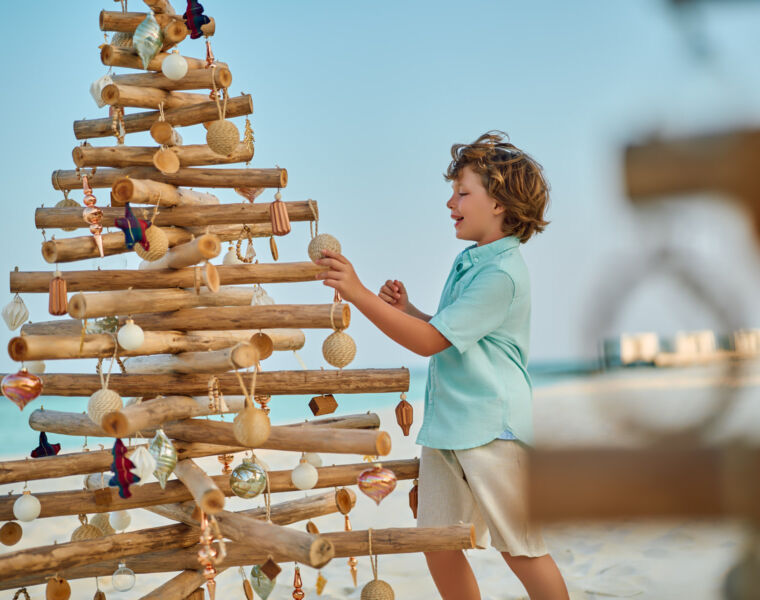 A young boy playing with a wooden tree