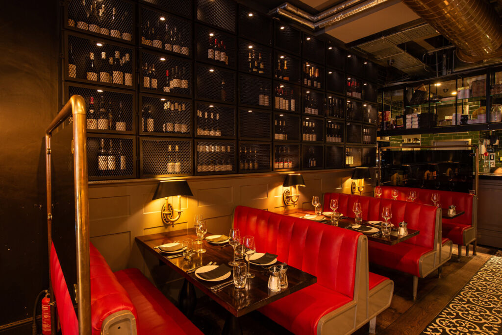 The cosy red leather dining booths next to walls holding fine wines