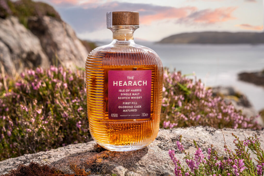 A bottle of Hearach Oloroso Cask Matured sat on a rock with the sea behind