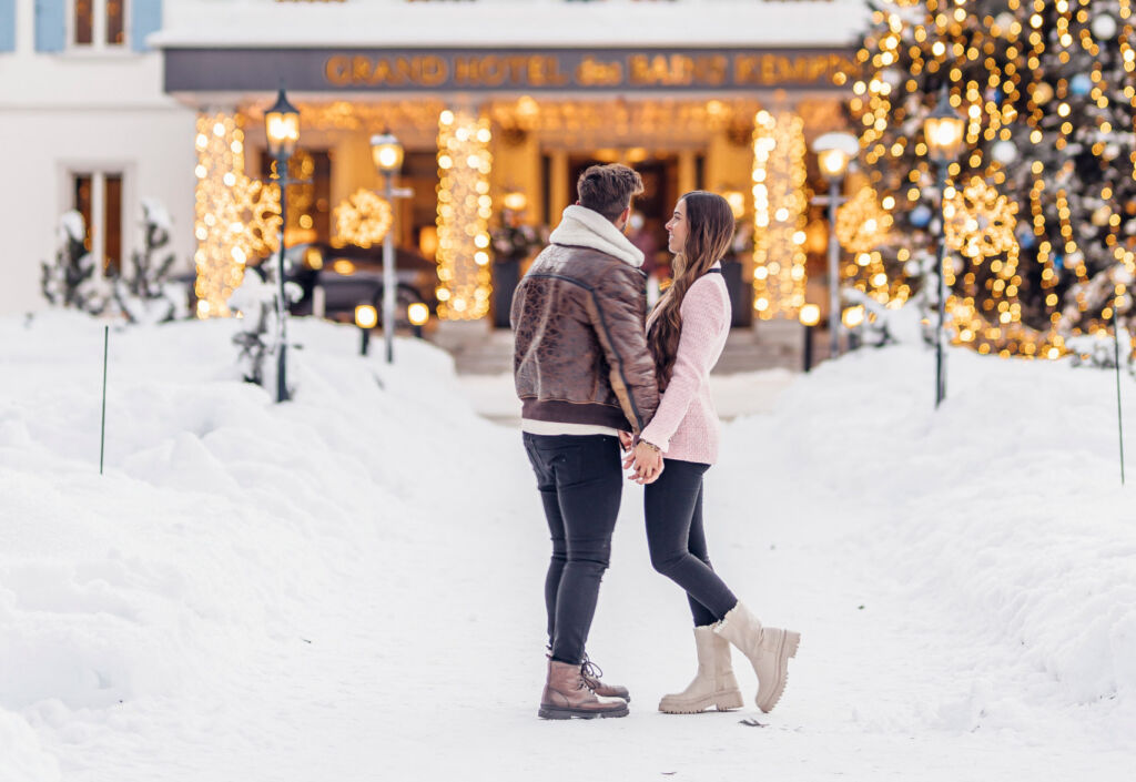 A couple holding hands in front of the hotel in St Moritz