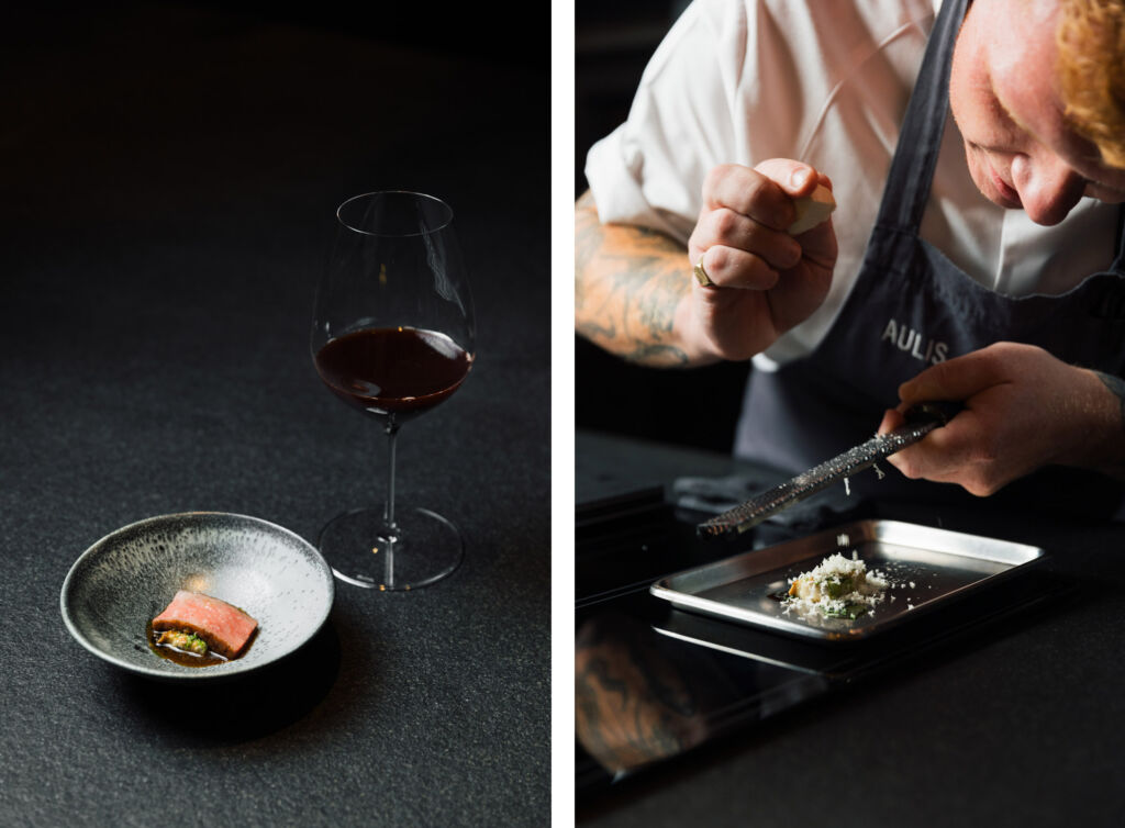 A glass of wine with a small plate and a dish being prepared