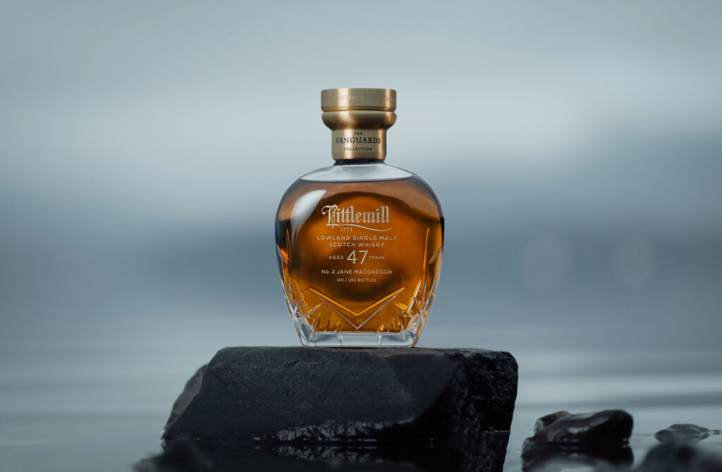 A bottle of the whisky placed on a flat topped rock on the shore