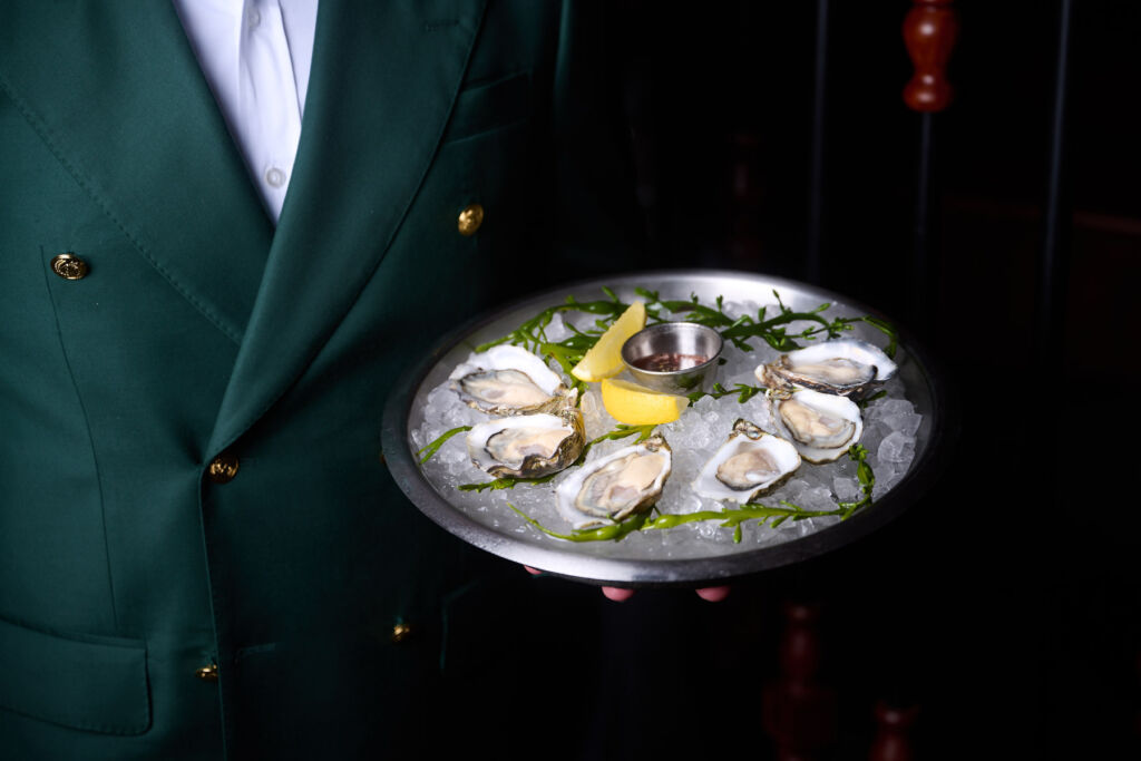 A member of staff bringing a tray of oysters