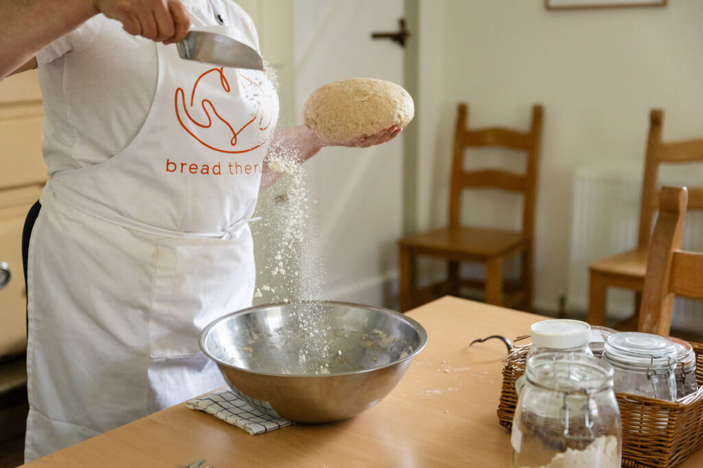 Pauling taking some freshly kneaded dough from a metal bowl