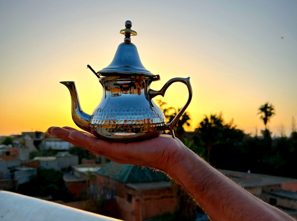 Simon holding a hand-worked teapot against the skyline at sunrise