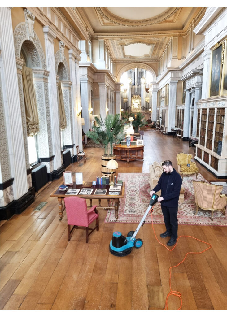 A team member using a vacuum cleaner in a vast hall