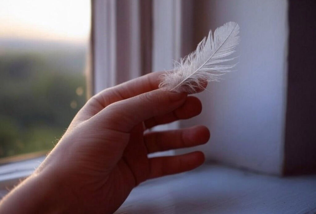 A person using a feather to locate drafts from his window